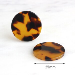 May include: Two round, brown and yellow patterned resin hair clips, 25mm in diameter.
