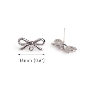 May include: Two silver-colored bow-shaped stud earrings. One earring is positioned upright, showing the post. The other earring is lying flat. The text indicates the bow is 0.6 inches (16mm) wide.