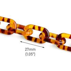 May include: A close-up of a brown and yellow plastic chain with a tortoiseshell pattern. The chain is 1.05 inches (27 mm) wide.