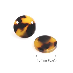 Op de afbeelding: Twee ronde kralen met schildpadpatroon, elk met twee gaten. De kralen hebben een diameter van 1,5 cm. De kralen hebben een mix van bruine, zwarte en gele kleuren.