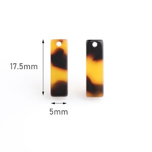 Op de afbeelding: Twee rechthoekige bedels van bruin en geel hars met een gat aan de bovenkant. De bedels zijn 17,5 mm lang en 5 mm breed.