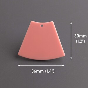 Może przedstawiać: Różowy plastikowy trójkąt z otworem na górze, o wymiarach 36 mm szerokości i 30 mm wysokości.