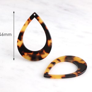 May include: Two brown and yellow tortoise shell teardrop shaped earrings with a hole at the top. The earrings are 46mm in length.