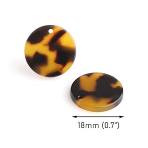 Könnte beinhalten: Zwei runde, braune und schwarze Resinscheiben mit einem Loch in der Mitte. Die Scheiben haben einen Durchmesser von 18 mm.