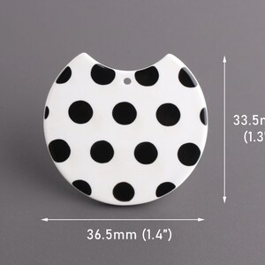 May include: White ceramic pendant with a black polka dot pattern. The pendant is 1.3 inches tall and 1.4 inches wide.