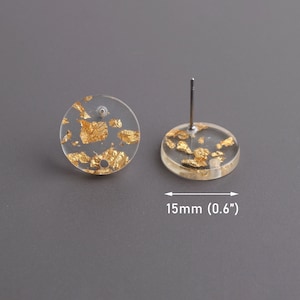 May include: A pair of gold flake stud earrings with clear resin backing. The earrings are 0.6 inches in diameter.