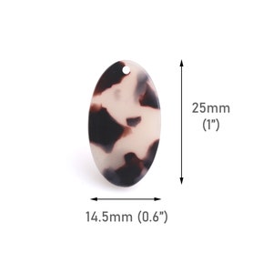 Könnte beinhalten: Ein ovaler Anhänger aus Harz in Weiß und Braun mit einem marmorierten Muster. Der Anhänger misst 2,5 cm im Durchmesser und 1,45 cm in der Breite.