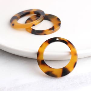 May include: Three brown and black tortoise shell plastic rings. The rings are all different sizes and have a smooth, glossy finish.