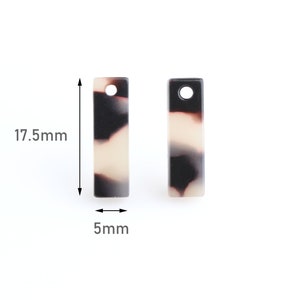May include: Two black and white patterned rectangular acrylic charms with a hole at the top. Each charm measures 17.5 mm in height and 5 mm in width.
