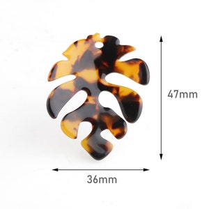 May include: A brown and black tortoise shell plastic leaf shaped hair clip, measuring 4.7 cm by 3.6 cm.