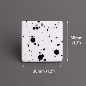 May include: White square tile with black splatter paint design. The tile measures 1.2 inches by 1.2 inches.