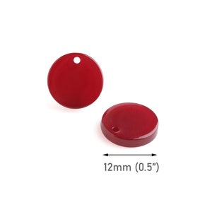 May include: Two red round plastic embellishments with a hole in the center. Each embellishment measures 0.5 inches in diameter.