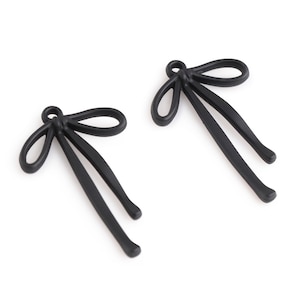 以下が含まれることがあります： 上部にループが付いた黒い金属製の弓形のチャーム2つ。弓は薄い金属製で、シンプルでエレガントなデザインです。