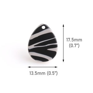 Könnte beinhalten: Schwarzer und weißer gestreifter Keramik-Anhänger mit einem Loch oben. Der Anhänger ist 1,75 cm hoch und 1,25 cm breit.