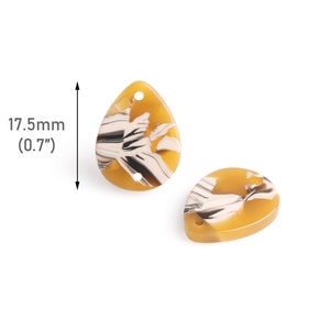May include: Two yellow and white teardrop-shaped resin beads with a swirl pattern. Each bead has two holes for stringing. The beads measure 0.7 inches in length.