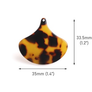 Könnte beinhalten: Ein brauner und gelber Schildpatt-Anhänger aus Kunststoff in Tropfenform. Der Anhänger ist 3,5 cm breit und 3,3 cm hoch.