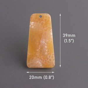 Pode incluir: Um pingente retangular de cor laranja claro com uma superfície texturizada. O pingente mede 39 mm de altura e 20 mm de largura.