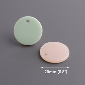 Puede incluir: Dos adornos redondos, planos y de plástico con un agujero en el centro. Los adornos tienen un diámetro de 20 mm y son de color verde claro y rosa claro.
