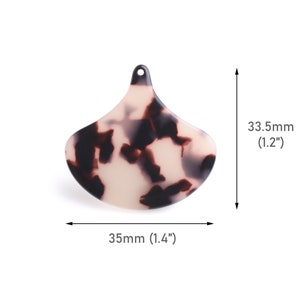 Könnte beinhalten: Eine weiße und schwarze Schildpatt-Haarklammer aus Kunststoff in Tropfenform. Die Klammer ist 3,5 cm breit und 3,0 cm hoch.