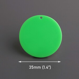 May include: A bright green, circular pendant with a small hole at the top for hanging. The pendant measures 1.4 inches (35mm) in diameter. The background is a solid gray.