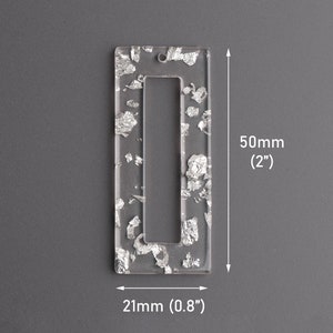 May include: A clear acrylic rectangle with a silver foil design. The rectangle has a rectangular opening in the center. The rectangle measures 2 inches by 0.8 inches.