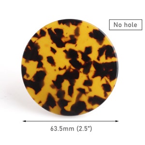 Könnte beinhalten: Ein runder Haarklammer aus Schildpatt in Braun und Gelb mit einem Durchmesser von 6,35 cm, ohne Loch. "No hole" ist in weißer Schrift auf weißem Hintergrund geschrieben.