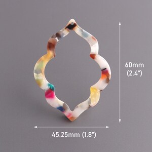 May include: A white, multi-colored, plastic earring with a scalloped design. The earring measures 2.4 inches in height and 1.8 inches in width.
