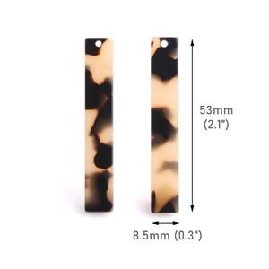 Puede incluir: Dos placas rectangulares de acrílico marrón y negro con un agujero en la parte superior. Las placas miden 53 mm de largo y 8,5 mm de ancho.