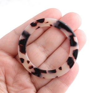 May include: A brown and white patterned plastic ring with a smooth, glossy finish.