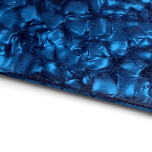 May include: Close-up of a blue and black marbled surface. The surface has a textured, iridescent finish.