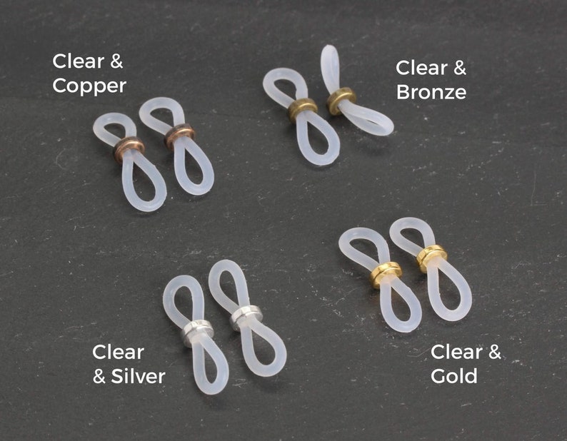 May include: Four pairs of clear silicone glasses strap holders with different colored metal accents: copper, bronze, silver, and gold.  "Clear & Copper", "Clear & Bronze", "Clear & Silver", and "Clear & Gold" are written below each pair.