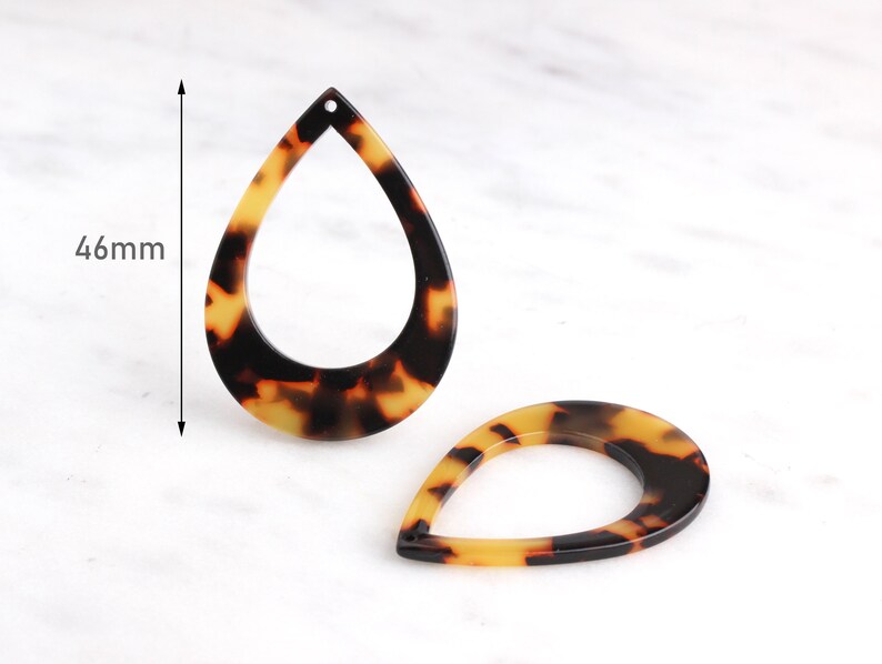 May include: Two brown and yellow tortoise shell teardrop shaped earrings with a hole at the top. The earrings are 46mm in length.