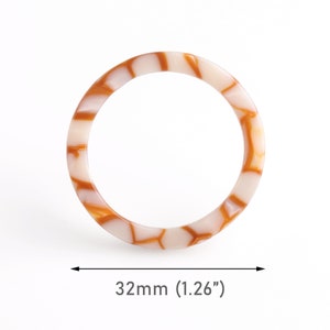 May include: A white and brown patterned bangle bracelet with a diameter of 1.26 inches.