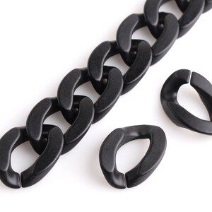 May include: A black plastic chain with two black plastic connector rings. The chain is made of large, flat links.