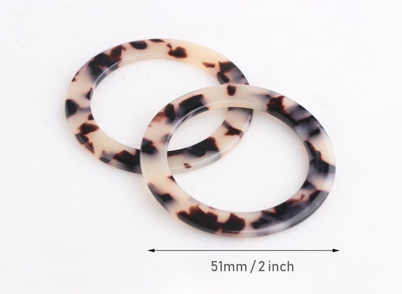 May include: Two brown and white patterned plastic rings, each with a diameter of 2 inches or 51 mm.
