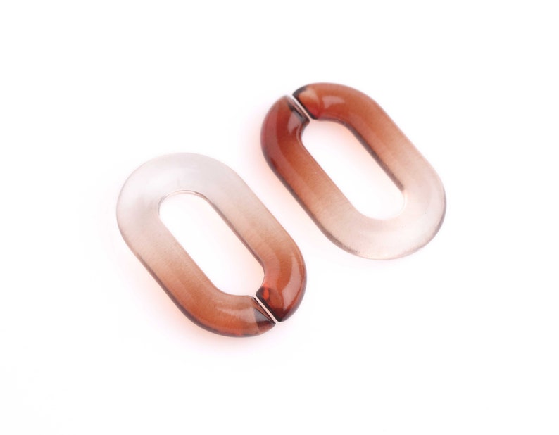 May include: Two oval-shaped, translucent brown acrylic links. The links have a gradient effect, transitioning from clear to a darker brown. The links are designed to connect, with a small opening on one side.