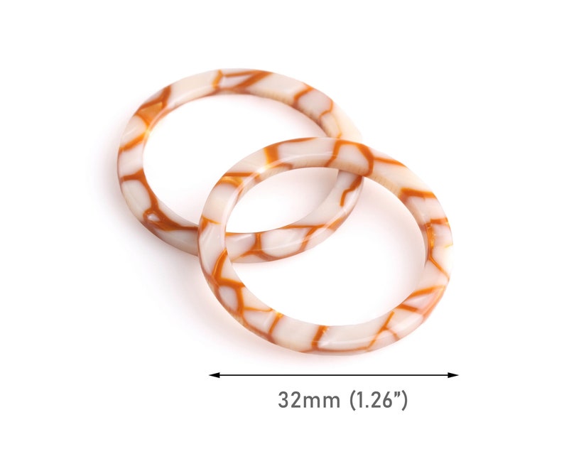 May include: Two white and brown patterned plastic rings, each measuring 1.26 inches in diameter.