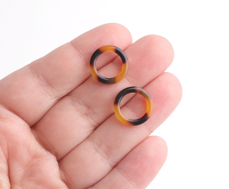 May include: Two small, round, brown and black patterned rings.