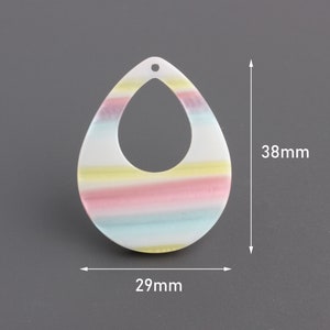 May include: A white teardrop-shaped earring with a rainbow stripe design. The earring measures 38 mm in height and 29 mm in width.