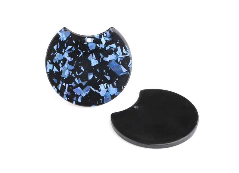 May include: Two black resin pendant charms, one with a blue and black iridescent pattern and the other solid black.