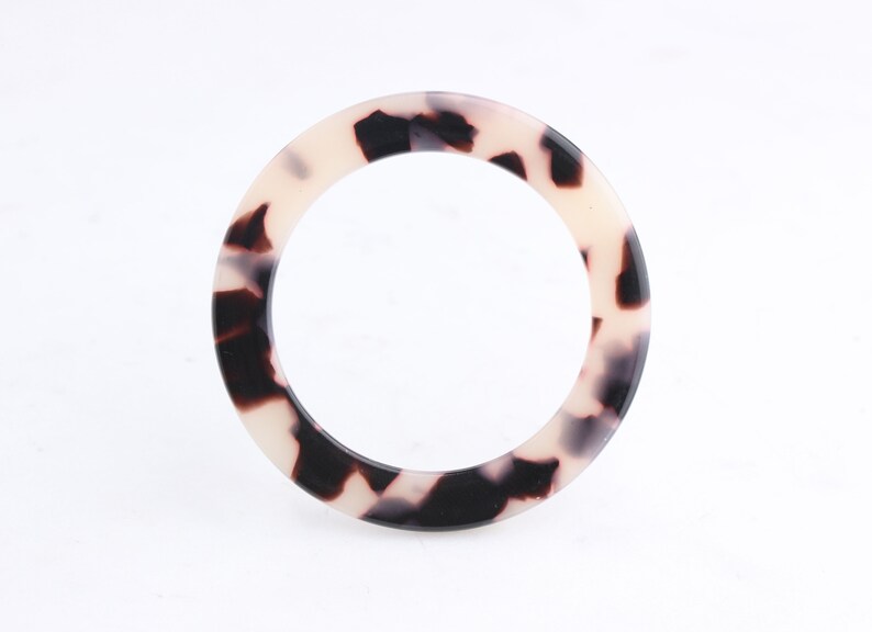 May include: A white and black tortoiseshell patterned plastic bangle bracelet.