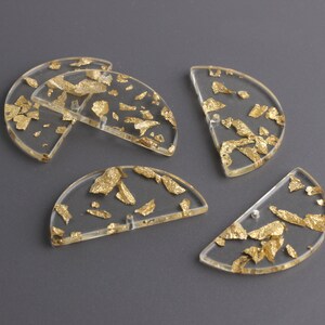 Puede incluir: Cinco formas de medio c&iacute;rculo de acr&iacute;lico transparente con escamas de pan de oro incrustadas. Las formas tienen un di&aacute;metro de aproximadamente 5 cm.