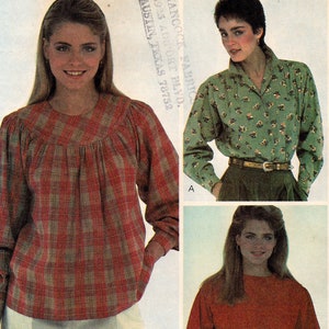 May include: Three women's blouses with long sleeves. The first blouse is red and white plaid. The second blouse is green with a floral print. The third blouse is solid red. All three blouses have a round neckline and are worn with a belt.