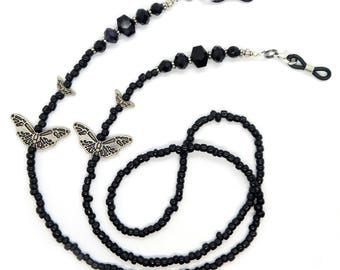 May include: Black beaded eyeglass chain with silver butterfly charms and black crystal beads. The chain has two silver clasps for attaching to glasses.