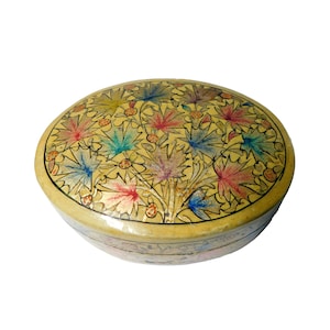 May include: An oval-shaped, cream-colored box with a floral design. The box is decorated with colorful leaves and flowers in shades of blue, green, red, and yellow.