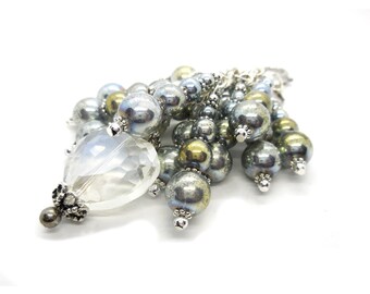 May include: A silver charm with a clear crystal heart and a cluster of iridescent silver and gold beads.