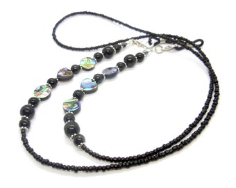 May include: Black beaded eyeglass chain with abalone shell accents. The chain features small black beads, larger black beads, and iridescent abalone shell pieces. Silver-toned metal connectors and accents complete the design.