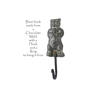 May include: A bear-shaped hook made from a chocolate mold. The hook has a ring to hang it from. Bear hook made from a chocolate mold with a hook and a ring to hang it from.