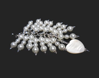 May include: A white pearl and silver charm necklace with a white heart-shaped pendant.