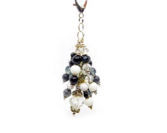 May include: A decorative charm featuring a cluster of black, white, and clear faceted beads suspended from a silver-toned metal lobster clasp. The arrangement includes round opaque beads, translucent crystal-like beads, and small metallic spacers.